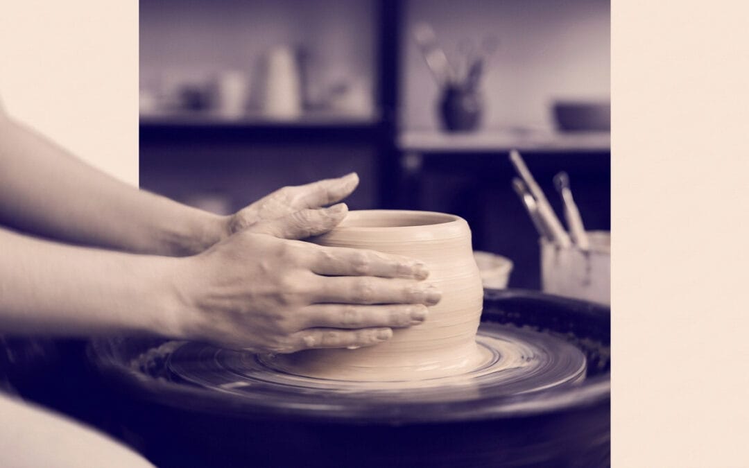 Gros plan sur les mains d'une personne façonnant un pot en argile sur un tour de potier dans un atelier artisanal.